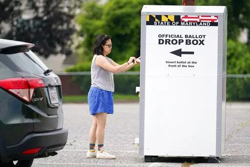 A woman drops a ballot into a drop box while casting her vote during Maryland's primary election, Tuesday, July 19, 2022, in Baltimore.  Whether a state requires voters to request an absentee ballot or participates in universal mail-in voting, all ballots cast by mail or dropped off at a drop box are vetted to ensure their legitimacy.(AP Photo/Julio Cortez, File)