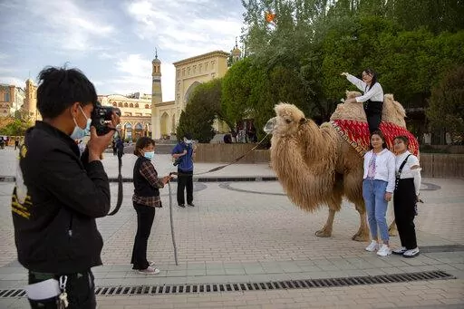 Tourists pose for photos with a camel outside the Id Kah Mosque in Kashgar in western China's Xinjiang Uyghur Autonomous Region, as seen during a government organized trip for foreign journalists, on April 19, 2021. After a U.N. report concluding that China's crackdown in the far west Xinjiang region may constitute crimes against humanity, China used a well-worn tactic to deflect criticism: blame a Western conspiracy. (AP Photo/Mark Schiefelbein, File)