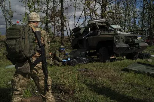 A Ukrainian national guard serviceman closes the bag containing the body of a Ukrainian soldier who was removed from an armored vehicle in an area near the border with Russia, in Kharkiv region, Ukraine, Monday, Sept. 19, 2022. This region of rolling fields and woodland near the Russian border was the site of fierce battles for months during the summer. Only now, after Ukrainian forces retook the area and pushed Russian troops back across the border in a blistering counteroffensive, has the coll