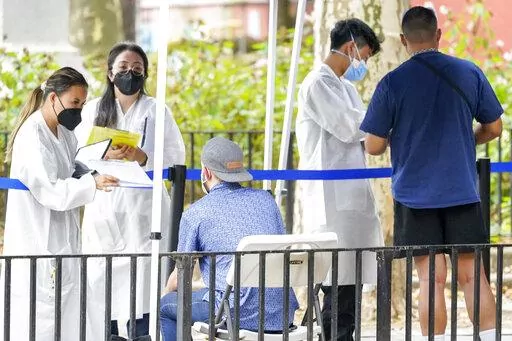 Healthcare workers with New York City Department of Health and Mental Hygiene help people register for the monkeypox vaccine at one of the City's vaccination sites, Tuesday, July 26, 2022, in New York. U.S. health officials said Thursday that the country’s monkeypox outbreak can still be controlled and eliminated, despite rising case numbers and concerns about limited vaccine supplies in many parts of the country. (AP Photo/Mary Altaffer)