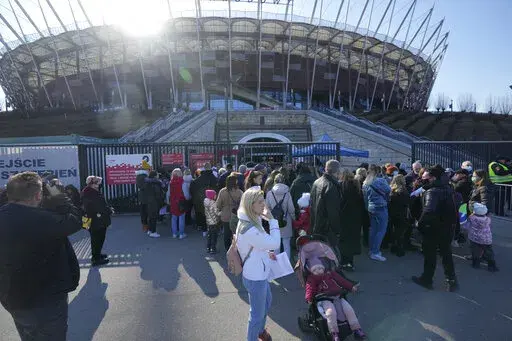 Hundreds of refugees from Ukraine wait in line to apply for Polish ID numbers that will entitle them to work, free health care and education, at a special application point at the National Stadium in Warsaw, Poland, on Saturday, March 19, 2022. The application points are not able to handle all those interested and ask many of them to return. (AP Photo/Czarek Sokolowski)