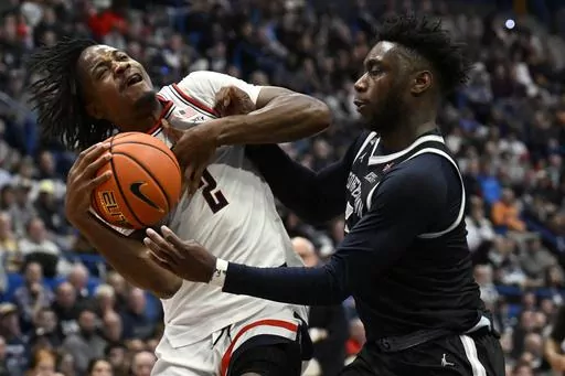 UConn guard Tristen Newton, left, is fouled by Georgetown guard Jay Heath in the second half of an NCAA college basketball game, Sunday, Jan. 14, 2024, in Hartford, Conn. (AP Photo/Jessica Hill)