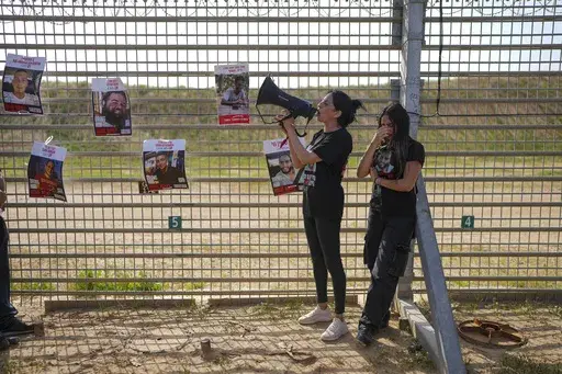 Relatives of hostage held by Hamas in the Gaza Strip, stand by the Israe-Gaza border fence, calling for their release and expressing concerns that the resumption of fighting in Gaza puts their loved ones at risk, in southern Israel, Tuesday, March 18, 2025. (AP Photo/Ohad Zwigenberg)