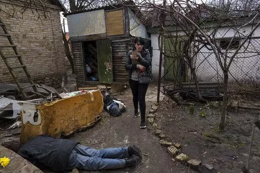 Ira Gavriluk holds her cat as she walks next to the corpses of her husband and her brother, who were killed in Bucha, on the outskirts of Kyiv, Ukraine, Monday, April 4, 2022. (AP Photo/Rodrigo Abd, File)