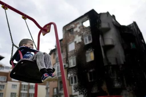 Yarik sits in a swing at a playground outside a building destroyed during attacks in Irpin, Ukraine, on the outskirts of Kyiv, on Monday, May 30, 2022. (AP Photo/Natacha Pisarenko)