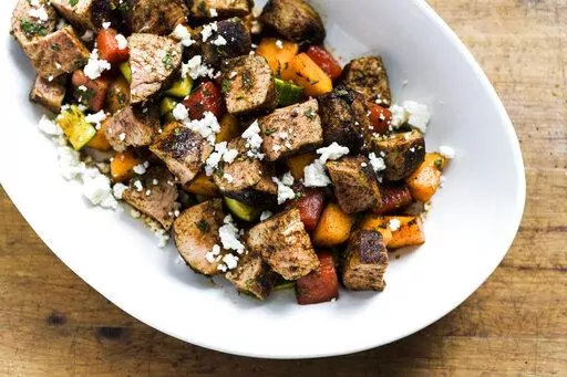 This image released by Milk Street shows a recipe for Chili-rubbed Pork with Cucumber-Melon Salad. (Milk Street via AP)