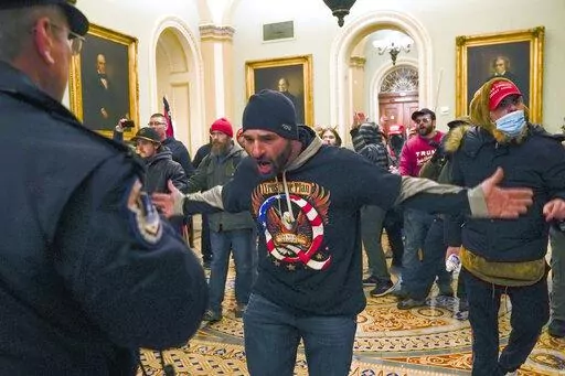 In this Jan. 6, 2021, photo, Trump supporters, including Douglas Jensen, center, confront U.S. Capitol Police in the hallway outside of the Senate chamber at the Capitol in Washington. The Iowa construction worker and QAnon follower was sentenced Friday, Dec. 16, 2022, to five years in prison for his role in the Jan. 6, 2021, insurrection at the U.S. Capitol, when he led a crowd chasing a police officer who diverted rioters away from lawmakers. (AP Photo/Manuel Balce Ceneta, File)