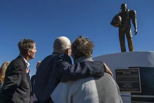 Apollo 13 astronaut Fred Haise Jr., center, hugs sculptor Mary Ott Tremmel Davidson as her statue honoring Haise is unveiled at Biloxi Beach in Biloxi, Miss., Sunday, Feb. 13, 2022. The original ceremony, planned for the 50th anniversary of Apollo 13 in April 2020, was canceled because of COVID-19. Sunday’s event went on despite the death of Haise’s wife, Patt, less than a week before. (Hannah Ruhoff/The Sun Herald via AP)