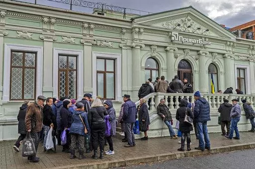 Residents queue at a bank branch in Kherson, southern Ukraine, Nov. 21, 2022. Even as Ukraine celebrates recent battlefield victories, its government faces a looming challenge on the financial front: how to pay the enormous cost of the war effort without triggering out-of-control price spikes for ordinary people or piling up debt that could hamper postwar reconstruction. (AP Photo/Bernat Armangue, File)