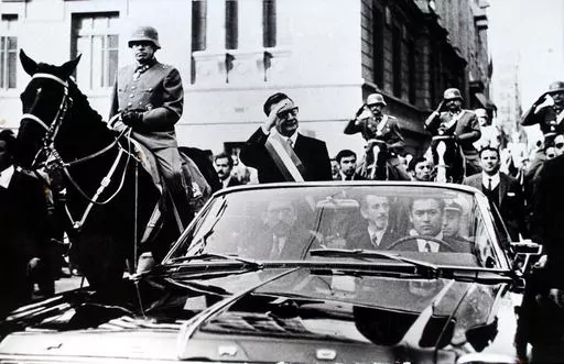 Chilean President Salvador Allende salutes from an open vehicle as General Augusto Pinochet rides on horseback at left in Santiago, Chile, May 21, 1972. (AP Photo/File)