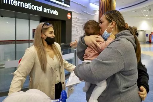 Families embrace after a flight from Los Angeles arrived at Auckland International Airport as New Zealand's border opened for visa-waiver countries Monday, May 2, 2022. New Zealand welcomed tourists from the U.S., Canada, Britain, Japan and more than 50 other countries for the first time in more than two years as it dropped most of its remaining pandemic border restrictions. (Jed Bradley/New Zealand Herald via AP)