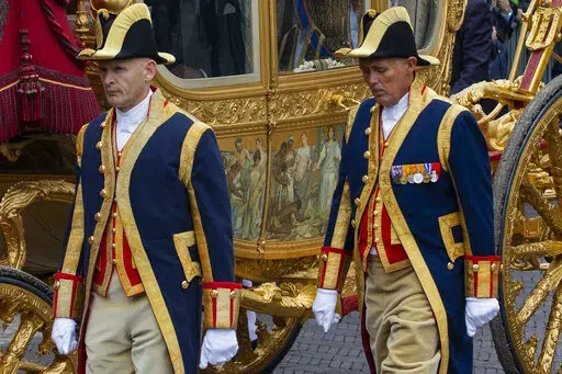 FILE- Footmen walk alongside the Golden Carriage as Netherlands' King Willem-Alexander and Queen Maxima arrive at Noordeinde Palace, after the King officially opened the new parliamentary year in The Hague, Netherlands, Tuesday Sept. 17, 2013. The Dutch king ruled out Thursday, Jan. 13, 2022, using in the near future the royal family's Golden Carriage, one side of which is decorated with a painting, center, that has drawn fire from critics who say it glorifies the Netherlands' colonial past, inc