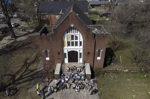 People worship on the steps of the Rolling Fork United Methodist Church, right, as damage is visible to surrounding properties, Sunday, March 26, 2023, in Rolling Fork, Miss. Emergency officials in Mississippi say several people have been killed by tornadoes that tore through the state on Friday night, destroying buildings and knocking out power as severe weather produced hail the size of golf balls moved through several southern states. (AP Photo/Julio Cortez)