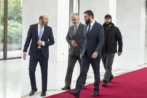 Syria's de facto leader Ahmad al-Sharaa, foreground, formerly known as Abu Mohammed al-Golani, walks in the presidential palace ahead of his meeting with Walid Ellafi, Libyan minister of state for communication and political affairs, in Damascus, Saturday, Dec. 28, 2024. (AP Photo/Mosa'ab Elshamy)