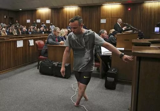 FILE — Oscar Pistorius, walks on his stumps during argument in mitigation of sentence by his defense attorney Barry Roux in the High Court in Pretoria, South Africa, Wednesday, June 15, 2016. An appeals court found Pistorius guilty of murder and not a lesser charge of culpable homicide for the shooting death of his girlfriend Reeva Steenkamp. Pistorius shot his girlfriend Reeva Steenkamp more than a decade ago in a Valentine's Day killing that jolted the world and shattered the image of a spor
