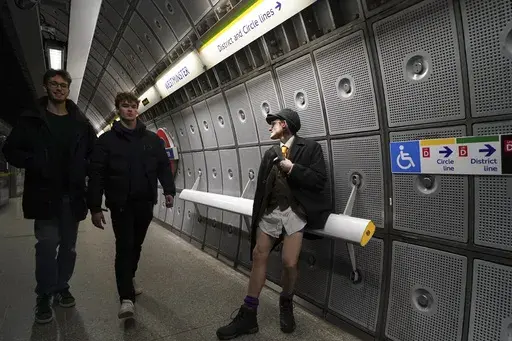 A man sits by the platform of an underground station, during the annual event "No Trousers Tube Ride" in London, Sunday, Jan. 12, 2025. (AP Photo/Alberto Pezzali)