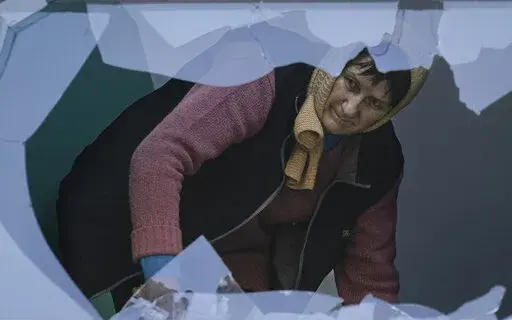 A woman cleans the staircase of broken glass at an apartment building damaged by bombing in Kyiv, Ukraine,Wednesday, March 23, 2022. The Kyiv city administration says Russian forces shelled the Ukrainian capital overnight and early Wednesday morning, in the districts of Sviatoshynskyi and Shevchenkivskyi, damaging buildings.(AP Photo/Vadim Ghirda)