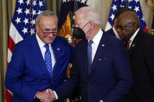 President Joe Biden shakes hands with Senate Majority Leader Chuck Schumer of N.Y., after signing the Democrats' landmark climate change and health care bill in the State Dining Room of the White House in Washington, Tuesday, Aug. 16, 2022. At back right is Rep. James Clyburn, D-S.C. (AP Photo/Susan Walsh)