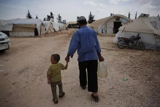 Syrians walk in a camp for internally displaced people in al-Bab, northern Syria, on May 29, 2018. The war in Ukraine helped push the global total of people left internally displaced by conflict or natural disasters to a record high of 71.1 million last year, according to a report released Thursday May 11, 2023. Syria had 6.8 million displaced by conflict after more than a decade of civil war. (AP Photo/Lefteris Pitarakis, File)