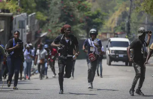 Journalists run for cover as protesters throw stones at a police car during a demonstration in Port-au-Prince, Haiti, March 19, 2025. (AP Photo/Odelyn Joseph, File)