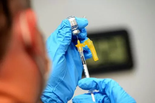 Ryan Dutton, an EMT from Rescue Inc., prepares shots of the Pfizer COVID-19 booster vaccine during a vaccine clinic held by Rescue Inc. at Leland & Gray Middle and High School, in Townshend, Vt., on Tuesday, Sept. 20, 2022. The updated COVID-19 boosters aren't an exact match to the newest omicron mutants but Pfizer says lab tests suggest its shot may offer some cross-protection.  (Kristopher Radder/The Brattleboro Reformer via AP, File)
