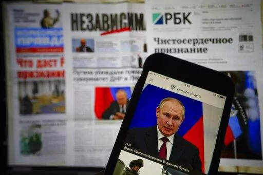 The app of the Russian government newspaper is displayed on an iPhone screen showing Russian President Vladimir Putin during his speech in the Kremlin in Moscow, Russia, Tuesday, Feb. 22, 2022. As the West sounds the alarm about the Kremlin ordering troops into eastern Ukraine and decries an invasion, Russian state media paints a completely different picture. It portrays the move as Moscow coming to the rescue of war-torn areas tormented by Ukraine’s aggression and bringing them much-needed pe