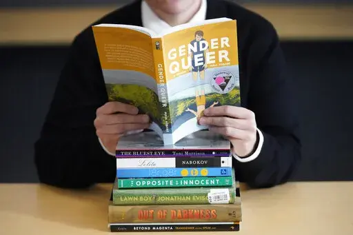 Amanda Darrow, director of youth, family and education programs at the Utah Pride Center, poses with books that have been the subject of complaints from parents in Salt Lake City on Dec. 16, 2021.  The wave of attempted book banning and restrictions continues to intensify, the American Library Association reported Friday. Numbers for 2022 already approach last year's totals, which were the highest in decades. (AP Photo/Rick Bowmer, File)