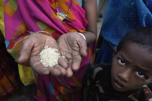 A woman from an impoverished family shows the sample of rice which she received under a government scheme offering free ration, on the outskirts of Patna, in the Indian state of Bihar, on May 11, 2024. (AP Photo/Manish Swarup)