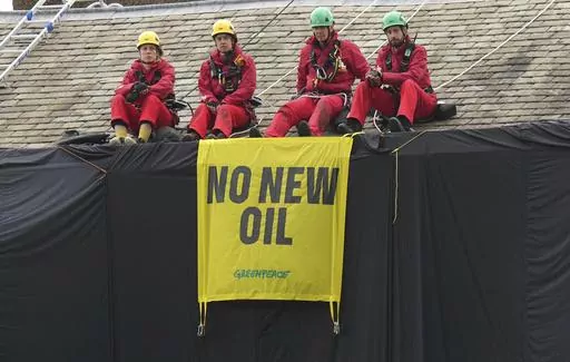 Greenpeace activists sit on the roof of Britain's Prime Minister Rishi Sunak's house in Richmond, North Yorkshire, England, after covering it in black fabric, Thursday Aug. 3, 2023. Greenpeace demonstrators draped the country estate of British Prime Minister Rishi Sunak in black fabric Thursday to protest his plan to expand oil and gas drilling in the North Sea. (Danny Lawson/PA via AP)
