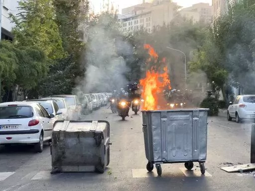In this Tuesday, Sept. 20, 2022, photo taken by an individual not employed by the Associated Press and obtained by the AP outside Iran, a trash bin is burning as anti-riot police arrive during a protest over the death of a young woman who had been detained for violating the country's conservative dress code, in downtown Tehran, Iran. Iran faced international criticism on Tuesday over the death of a woman held by its morality police, which ignited three days of protests, including clashes with se