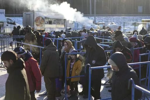Migrants queue to receive hot food at a logistics center at the checkpoint logistics center "Bruzgi" at the Belarus-Poland border near Grodno, Belarus, on Dec. 22, 2021. Poland’s conservative governing party was hoping to make migration a key campaign theme ahead of the country’s national election. But not like this. The Law and Justice party is being rocked by reports that Polish consulates issued visas in Africa and Asia in exchange for bribes, opening the door for migrants to enter the Eu