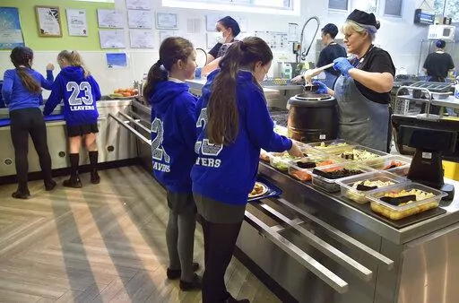 A general view of pupils during lunch hour at Hillstone Primary School, in Birmingham, England, Wednesday, Nov. 30, 2022. For some children in low-income areas in England, a school lunch may be the only nutritious hot meal they get in a day. School lunches are given for free to all younger children in England and to some of the poorest families. But the Food Foundation charity estimates that there are 800,000 children in England living in poverty who are not eligible for the free meals. (AP Phot