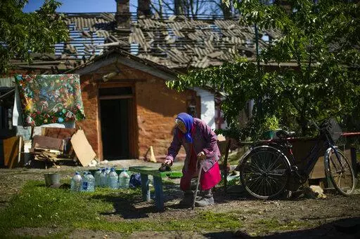 Local resident Valeria removes dust from a bench outside her heavily damaged house, background, after a Russian strike in Pokrovsk, eastern Ukraine, Wednesday, May 25, 2022. Two rockets struck the eastern Ukrainian town of Pokrovsk, in the Donetsk region early Wednesday morning, causing at least four injuries. (AP Photo/Francisco Seco)
