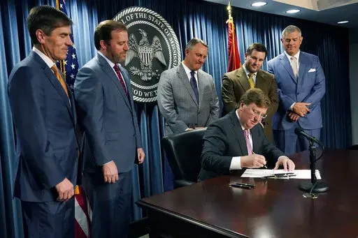 Republican Gov. Tate Reeves, seated, signs a bill that will reduce the state income tax over four years, beginning in 2023, at his office in Jackson, Miss., Tuesday, April 5, 2022. Attending the signing were from left, Senate Appropriations Committee Chairman Briggs Hopson, R-Vicksburg, Senate Finance Committee Chairman Josh Harkins, R-Flowood, House Speaker Pro Tempore Jason White, R-West, House Ways and Means Committee Chairman Trey Lamar, R-Senatobia and House Speaker Philip Gunn, R-Clinton. 