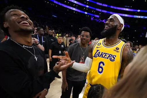 Los Angeles Lakers forward LeBron James, right, celebrates with his sons Bronny, left, and Bryce after passing Kareem Abdul-Jabbar to become the NBA's all-time leading scorer during the second half of an NBA basketball game against the Oklahoma City Thunder Tuesday, Feb. 7, 2023, in Los Angeles.(AP Photo/Ashley Landis)