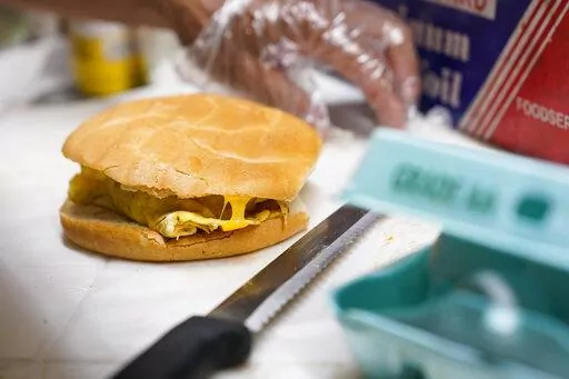 Hector Perez prepares to wrap a bacon, egg and cheese sandwich at a bodega in the Bronx section of New York, Friday, July 22, 2022. The cost of New York City's favorite breakfast is on the rise. The bacon, egg and cheese sandwich is easy to make, easy to eat on the go and cheap -- although not as cheap as it used to be. (AP Photo/Seth Wenig)