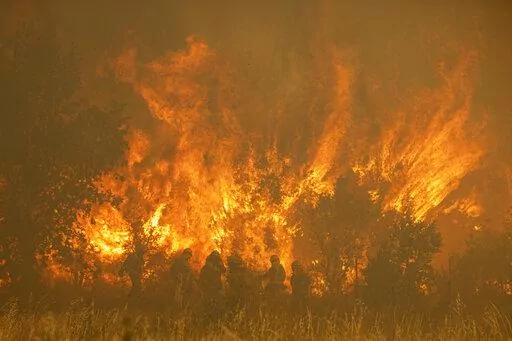 Firefighters work in front of flames during a wildfire in the Sierra de la Culebra in the Zamora Provence on Saturday June 18, 2022. Thousands of hectares of wooded hill land in northwestern Spain have been burnt by a wildfire that forced the evacuation of hundreds of people from nearby villages. Officials said the blaze in the Sierra de Culebra mountain range started Wednesday during a dry electric storm. (Emilio Fraile/Europa Press via AP)