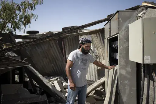 Bilal Hathaleen stands in the rubble of equipment providing electricity to residents of the West Bank village of Umm al-Khair, Wednesday, July 10, 2024. (AP Photo/Maya Alleruzzo)