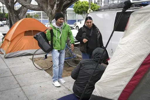 Members of the San Francisco Homeless Outreach Team, Edgar Tapia , left, and Maria B., talk to a homeless person in the Mission District, Tuesday, Sept. 10, 2024, in San Francisco. (AP Photo/Terry Chea)