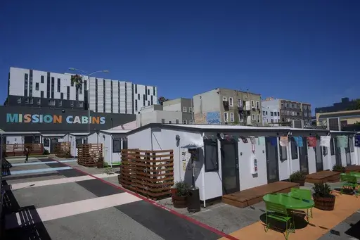 A person walks under a Mission Cabins sign at the Five Keys transitional housing location in San Francisco, Monday, Aug. 26, 2024. (AP Photo/Jeff Chiu)