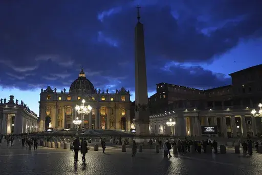 People walk at dusk in St Peter's Square at The Vatican, Thursday, Feb. 27, 2025. (AP Photo/Kirsty Wigglesworth, File)