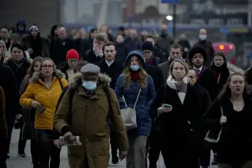 Workers walk over London Bridge towards the City of London financial district during the morning rush hour, in London, Monday, Jan. 24, 2022. For many in the U.K., the pandemic may as well be over. Mask requirements have been dropped everywhere and free mass testing is a thing of the past. The sense of freedom is widespread even as infections soared to record levels in Britain in March, driven by the milder but more transmissible Omicron BA.2 variant that’s rapidly spreading around Europe, the