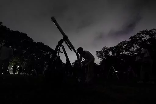A girl looks at the moon through a telescope in Caracas, Venezuela, on Sunday, May 15, 2022. The best day to spot five planets, Mercury, Jupiter, Venus, Uranus and Mars, lined up in the night sky is Tuesday, March 28, 2023, right after sunset. The five-planet array will be visible from anywhere on Earth, as long as you have clear skies. (AP Photo/Matias Delacroix)