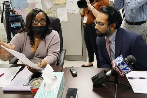 Commissioner RaToya Gilmer McGee, left, shows a ballot styles report to Amir Badat, an attorney for the NAACP Legal Defense Fund, during a meeting between the Hinds County Election Commission and a coalition of national and local civil rights organizations, Monday, Dec. 18, 2023, in Jackson, Miss. The commissioners said ballot shortages, technical mishaps and insufficient training were some of the factors that hampered voting in Mississippi's largest county during the Nov. 7 general election. (A