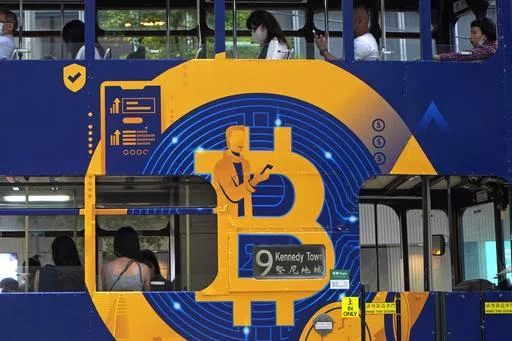 An advertisement for the cryptocurrency Bitcoin displayed on a tram, May 12, 2021, in Hong Kong. Sometime in the next few days or even hours, the “miners” who chisel bitcoins out of complex mathematics are going to take a 50% pay cut — effectively slicing new emissions of the world’s largest cryptocurrency in an event called bitcoin halving. (AP Photo/Kin Cheung, File)