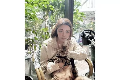 In this photo taken and provided by Pao Jo-yee, model Abby Choi, holding a cat, poses for a photo on Feb. 11, 2023, in Hong Kong. The ex-husband and former in-laws of the slain Hong Kong model were put in custody without bail Monday, Feb. 27, 2023, on a joint murder charge, after police found parts of her body in a refrigerator.(Pao Jo-yee via AP)
