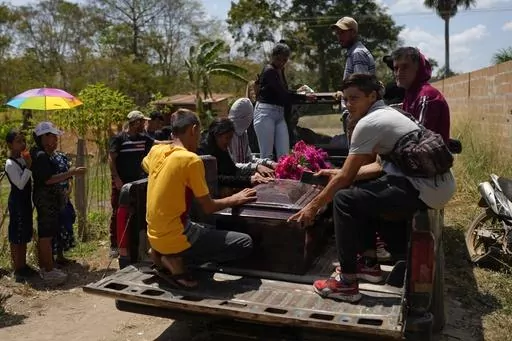The coffin that contains the remains of miner Gerson Leal, is transported in the bed of a truck to a cemetery in La Paragua, Bolivar state, Venezuela, Thursday, Feb. 22, 2024. The collapse of an illegally operated open-pit gold mine in central Venezuela killed at least 14 people including Leal and injured several more, state authorities said Wednesday, as some other officials reported an undetermined number of people could be trapped. (AP Photo/Ariana Cubillos)