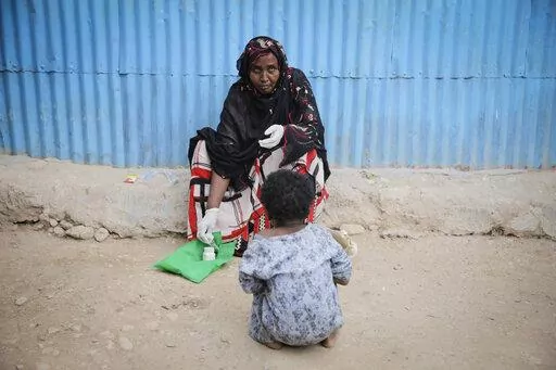 Safia Ibrahim demonstrates for the camera the tools and techniques she uses to perform female genital mutilation (FGM), which she learned at the age of 15 and has been practising for 35 years, as her neighbours daughter looks on in the courtyard of her home in Hargeisa, Somaliland, a semi-autonomous breakaway region of Somalia, on Feb. 7, 2022. Officials and health workers say cases of female genital mutilation increased during the pandemic in parts of Africa and particularly in Somaliland where