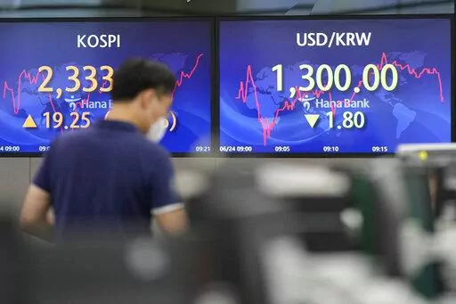A currency trader walks by the screens showing the Korea Composite Stock Price Index (KOSPI), left, and the foreign exchange rate between U.S. dollar and South Korean won at a foreign exchange dealing room in Seoul, South Korea, Friday, June 24, 2022. Shares were higher in Asia on Friday, tracking gains on Wall Street, where the market is headed for its first weekly gain after three weeks of punishing losses. (AP Photo/Lee Jin-man)