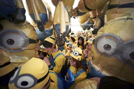 Participants dressed as minion characters from the "Despicable Me" franchise walk through minion balloons during the Minions Run in Tokyo on Feb. 13, 2016. This summer, the goggle-wearing yellow ones will return  in “Minions: Rise of Gru," in theaters July 1. The “Despicable Me” franchise and its “Minions” spinoffs are the highest grossing animated film franchise ever with more than $3.7 billion in tickets sold worldwide. (AP Photo/Eugene Hoshiko, File)